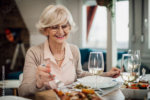 Happy mature woman enjoying in lunch at dining table.