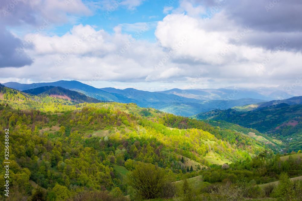 rural landscape in mountains. dappeled light on forested hills. beautiful nature scenery in spring. wonderful weather with clouds