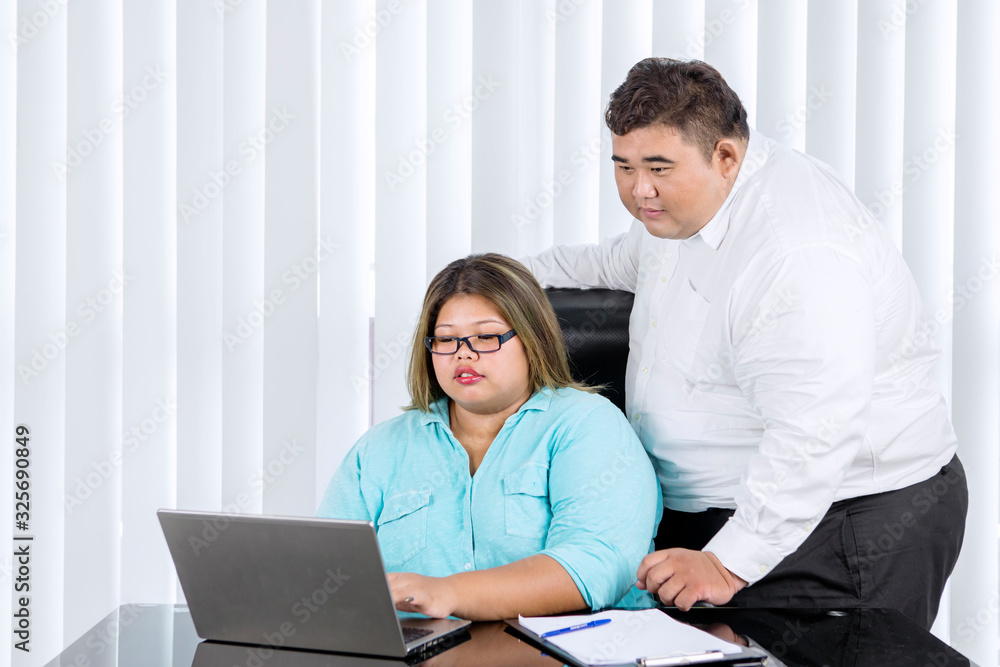 Fat man supervising her female employee working Fat man supervising her female employee working