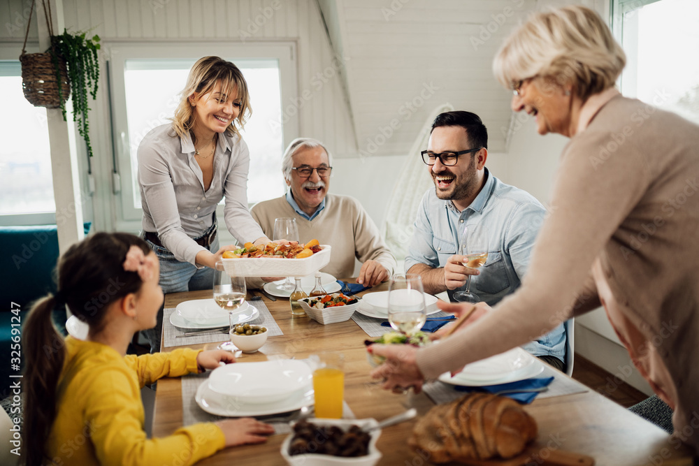 Cheerful multi-generation family having fun during lunch at dining table. Cheerful multi-generation family having fun during lunch at dining table.