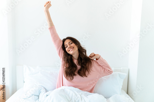 Wallpaper Mural Woman indoors at home lies in bedroom in bed stretching. Torontodigital.ca