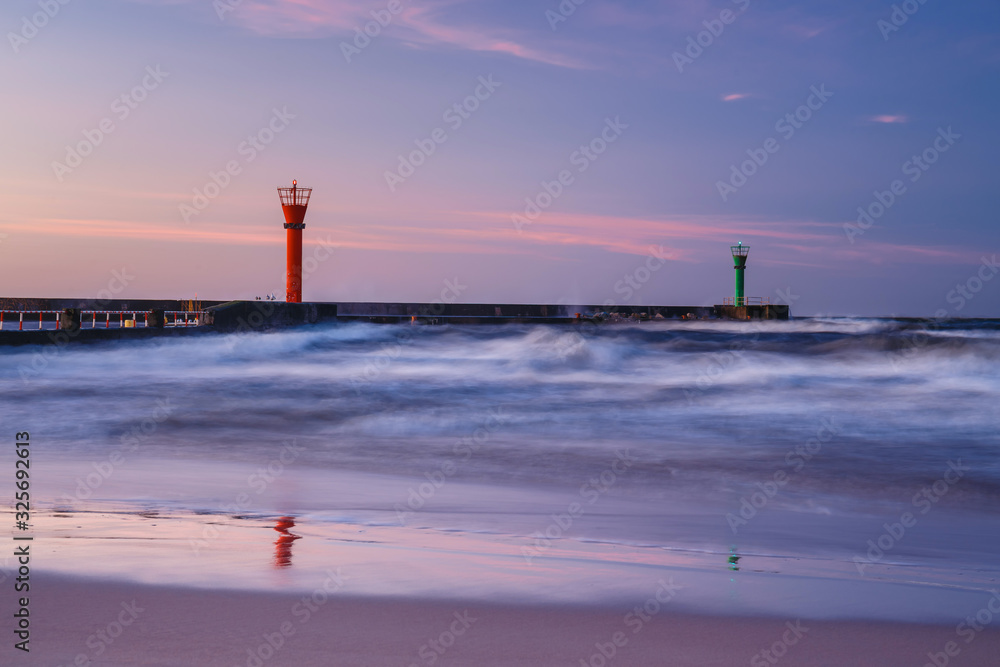 beautiful sunset with lighthouse and blue clouds over the sea