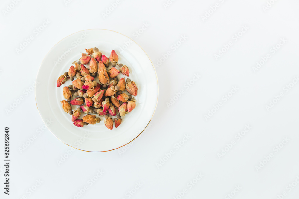 Rose herbal tea.Small dried rose on the plate.White background.Minimalist style.Copy space Rose herbal tea.Small dried rose on the plate.White background.Minimalist style.Copy space
