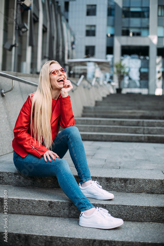 Young blonde hipster woman Smiling blonde woman laughing on the street cheerfully. Lovely young lady feeling happy