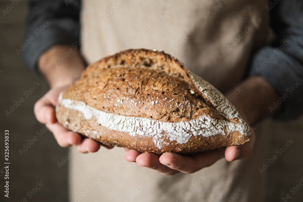Man in rustic apron holding a loaf of bread in his hands Man in rustic apron holding a loaf of bread in his hands
