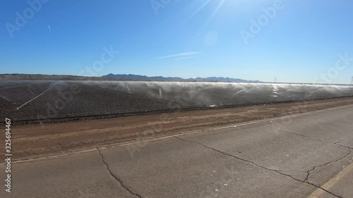 Driving by active irrigation sprinklers in newly planted field – Arizona