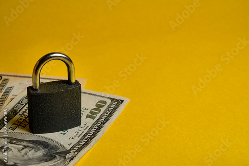 dollar banknotes and metal padlock at yellow background. Safety shopping, personal finances security, money savings