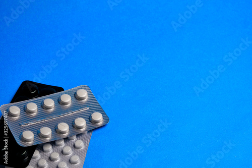 Pills in a blister at classic blue background with copy space