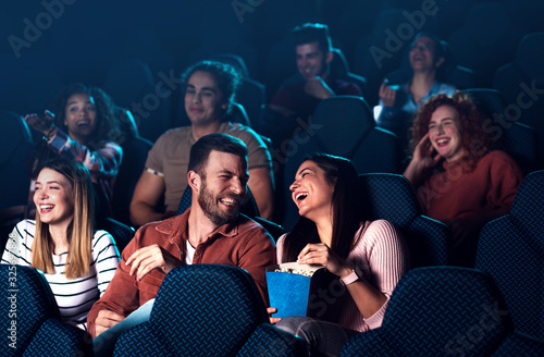 Group of cheerful people laughing while watching movie in cinema. photo