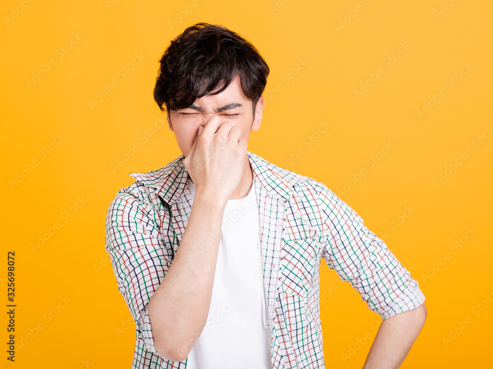 young man pinches nose with fingers . disgust something stinks bad smell young man pinches nose with fingers . disgust something stinks bad smell