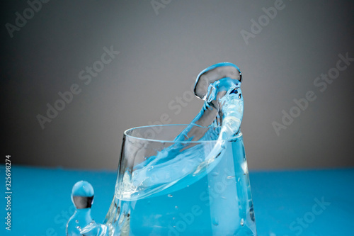 Splashes of water in a glass frozen in the form of unusual figures on a blue background.