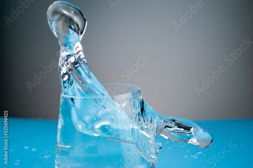 Splashes of water in a glass frozen in the form of unusual figures on a blue background.