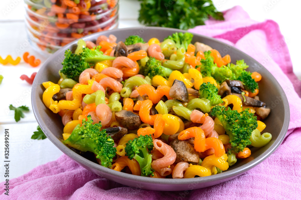 Cavatappi colored pasta with broccoli and mushrooms on a white wooden background. Pasta colorata. Pasta with vegetables Cavatappi colored pasta with broccoli and mushrooms on a white wooden background. Pasta colorata. Pasta with vegetables