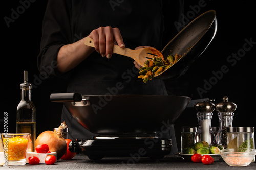 Chef adds vegetables to meat. Freeze in motion. Cooking delicious food. Chef in the kitchen. Recipe book, restaurant menu.