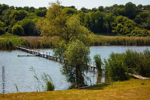 Beautiful wooden bridhe over the Tyasmin river with blue water in Razymivka (Rozymovka) village in Kirovograd region, Ukraine. Nature concept. Tyasmin river is a tributary of the Dnieper river.  photo