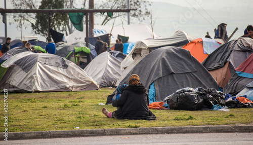 Spontaneous refugee camp by a gas station on the highway in the north of Greece, close to Idomeni. An old refugee sitting on the ground.  March 22nd 2016 photo