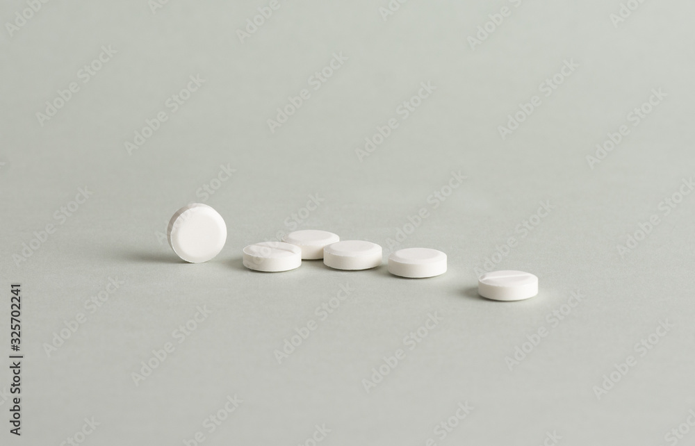 Isolated white tablets on grey background.