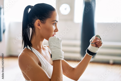 Fotografia Young boxer woman posing in combat stance in gym