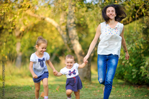 Happy family. Mom with daughters plays and rests in a beautiful park at sunset, family time.