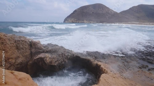 Seascape. Beach El Playazo, Cabo de Gata, province AlmerĂ­a, Andalusia Spain. Rocky sea shore with waves splashing in slow motion. Tourist site photo