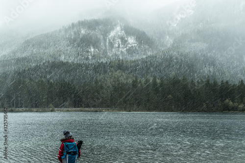 backpacker looks to the lake in the mountains of Bavaria, rainy day, Hintersee Ramsau