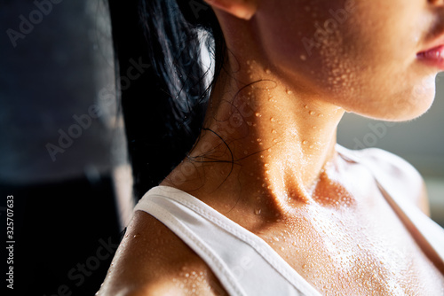 Close up shoulders and neck of sporty girl in drop of sweat on skin after workout