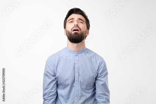 Fotografía Young gloomy man with beard pouting and crying, standing upset and depressed