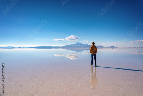 Young man watching the scenery and miror effect in Salar de Uyuni (Uyuni salt flats), Potosi, Bolivia, South America photo