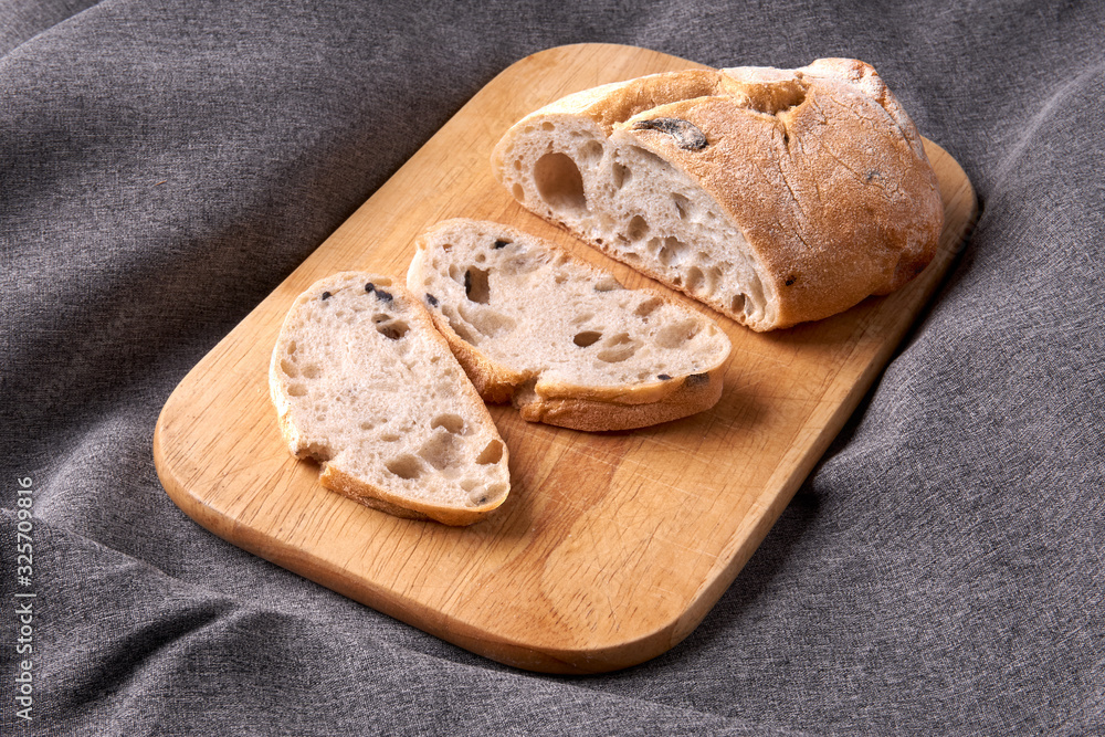 Ciabatta cut into slices on a wooden cutting board. Fresh diet homemade bread baked according to a traditional Italian recipe. Ciabatta cut into slices on a wooden cutting board. Fresh diet homemade bread baked according to a traditional Italian recipe.