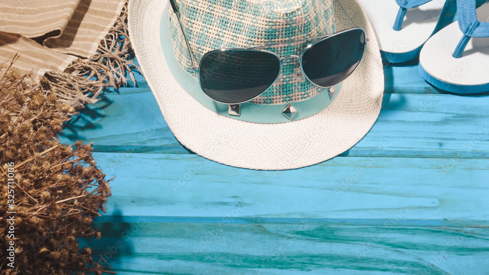 Slippers and a hat and sunglasses on a blue wooden floor Summer concept
