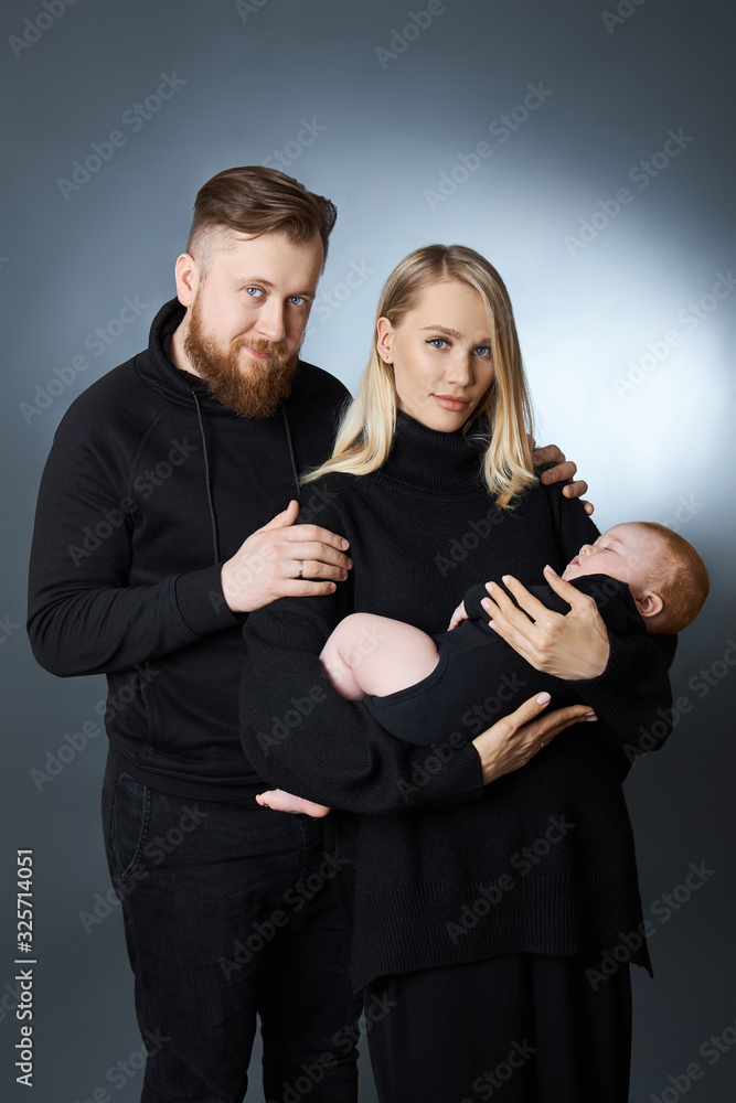 Man and a woman hold a baby in their arms. Portrait of a married couple after the birth of a child. Young family Man and a woman hold a baby in their arms. Portrait of a married couple after the birth of a child. Young family