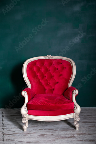 Antique velvet red armchair near emerald wall. red armchair Isolated on green background. Vintage chair on living room. furniture home. Insulated furniture. classic interior red sofa, closeup couch.