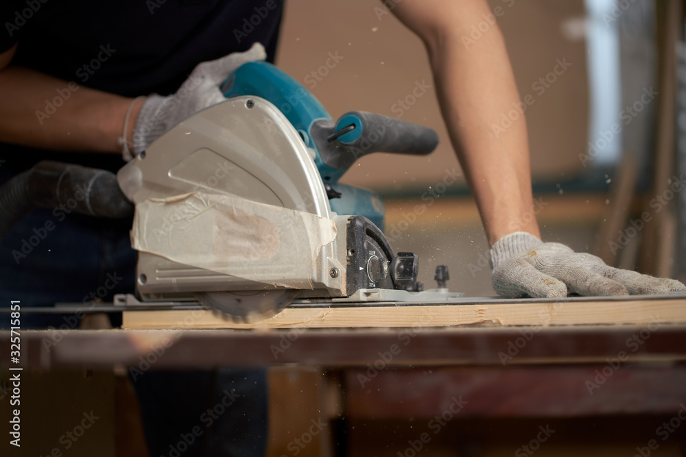 Carpenter man in white gloves works on jigsaw Carpenter man in white gloves works on jigsaw