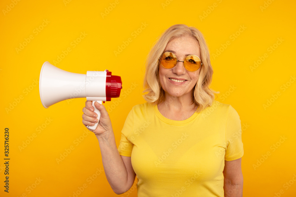 Naklejka premium Woman with megaphone isolated in the yellow studio