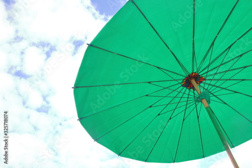Big green umbrella against the sky background