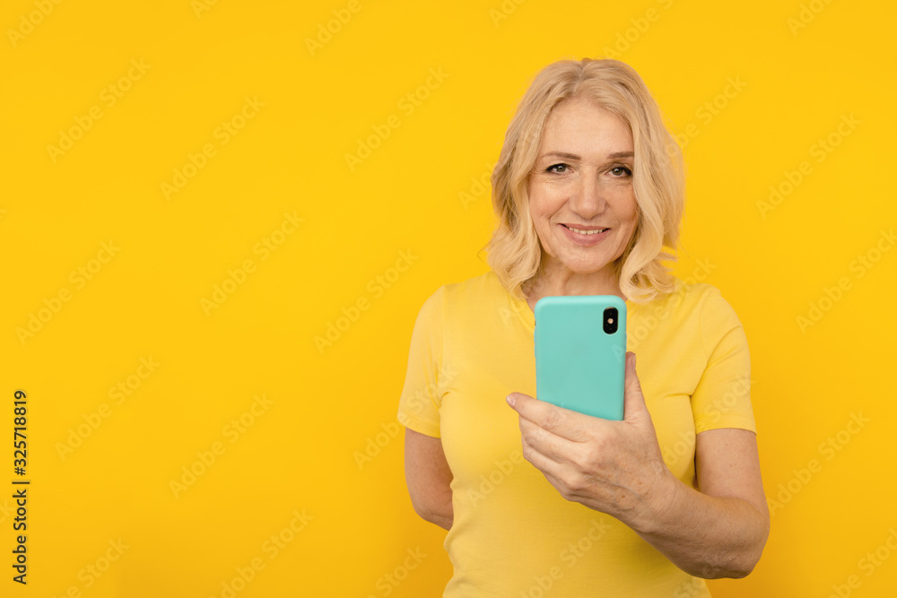 Pretty adult lady in bright clothes watching camera and posing with blue phone