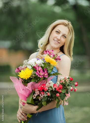 young woman with a bouquet of flowers on a blurred background of nature