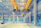Concrete floor inside factory or warehouse building with empty space for industry background. Overhead crane or bridge crane include hoist lifting for transportation, manufacturing, and production.