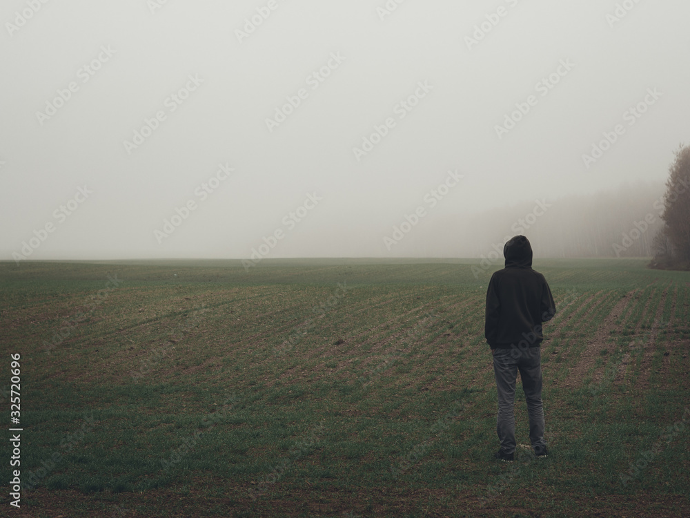 Alone man stands in an empty misty field. Autumn misty landscapes