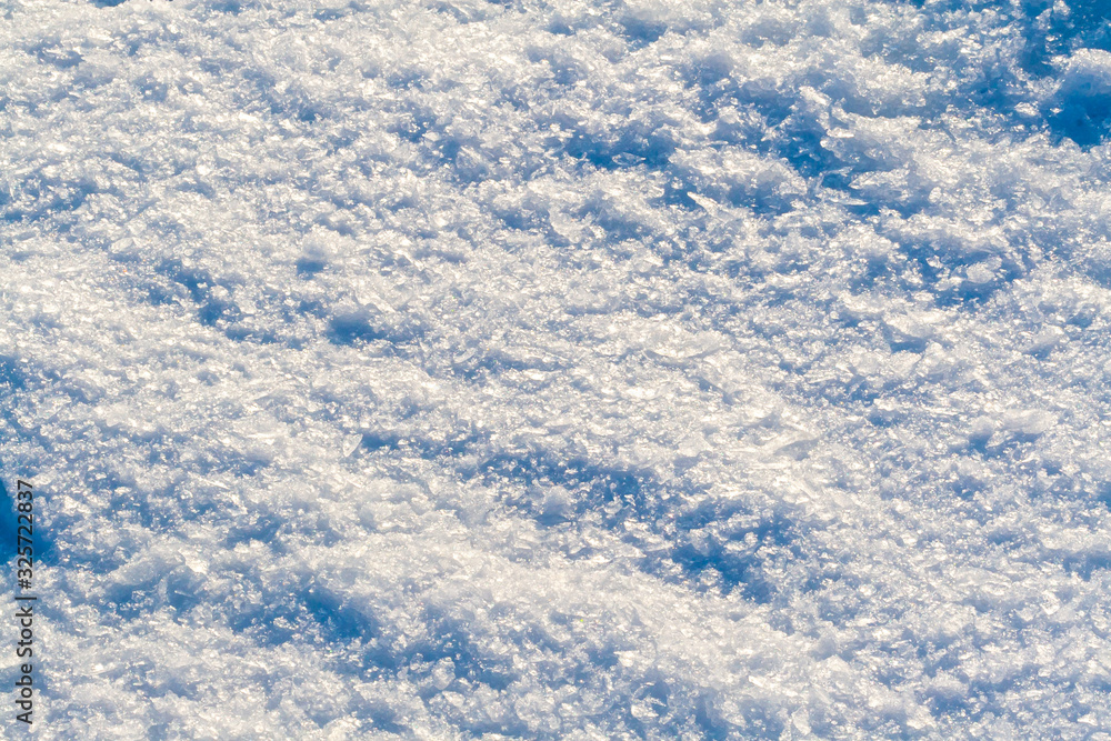 Snow surface of large ice crystals, close-up, shimmering with different colors.