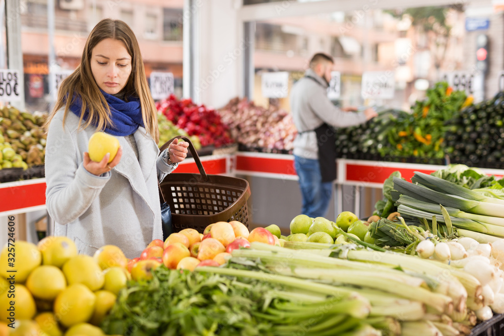 Female shopper picks apples at grocery store