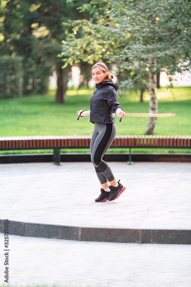 Fitness woman jumping on a rope outdoor in urban environment