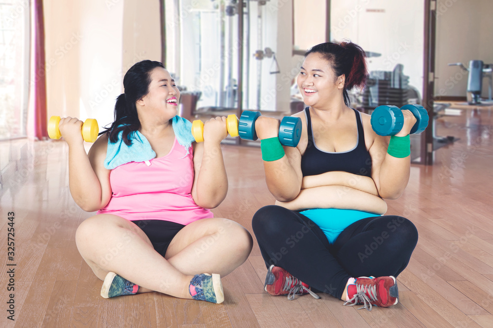 Obese women doing workout while sitting at gym