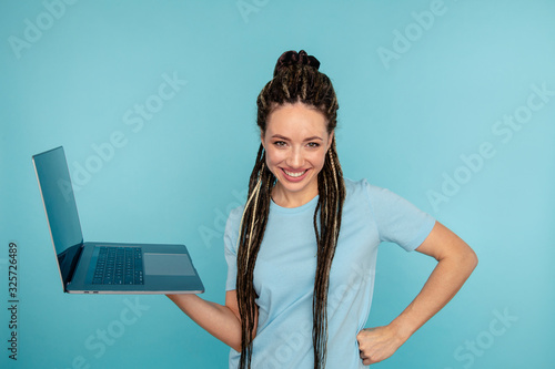 Portrait of happy exited young lady with laptop isolated over the blue studio