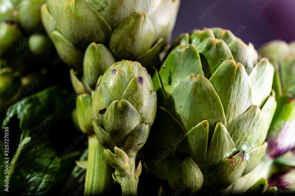 Obraz premium Cooking with fresh green artichokes heads, tasty vegetarian food
