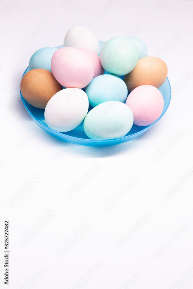 Huevos de pascua de colores en plato azul sobre fondo blanco Huevos de pascua de colores en plato azul sobre fondo blanco