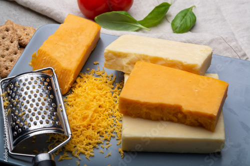 Cheese collection, matured and orange original British cheddar cheese in blocks and grated served on grey plate
