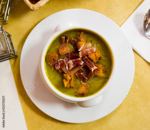 Top view of creamy zucchini soup with croutons and jamon