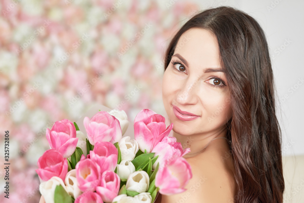 Beautiful girl with tulip flowers in hands on floral background. Greeting card for Women's Day March 8 or Mother's Day.Very nice florist woman holding beautiful colourful blossoming flowers bouquet Beautiful girl with tulip flowers in hands on floral background. Greeting card for Women's Day March 8 or Mother's Day.Very nice florist woman holding beautiful colourful blossoming flowers bouquet
