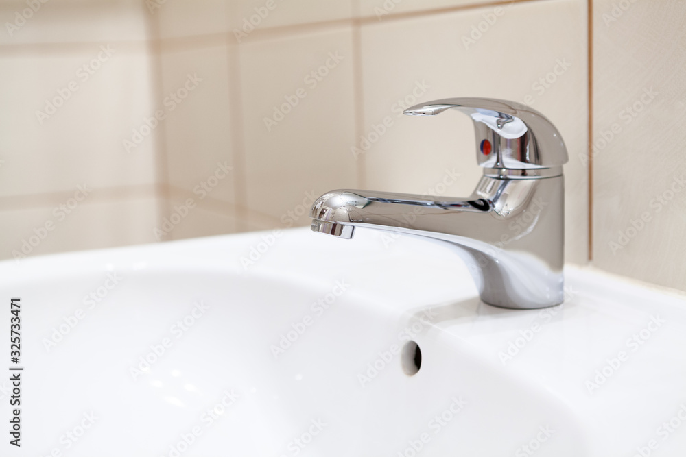 Stainless water tap in white bathroom sink Stainless water tap in white bathroom sink